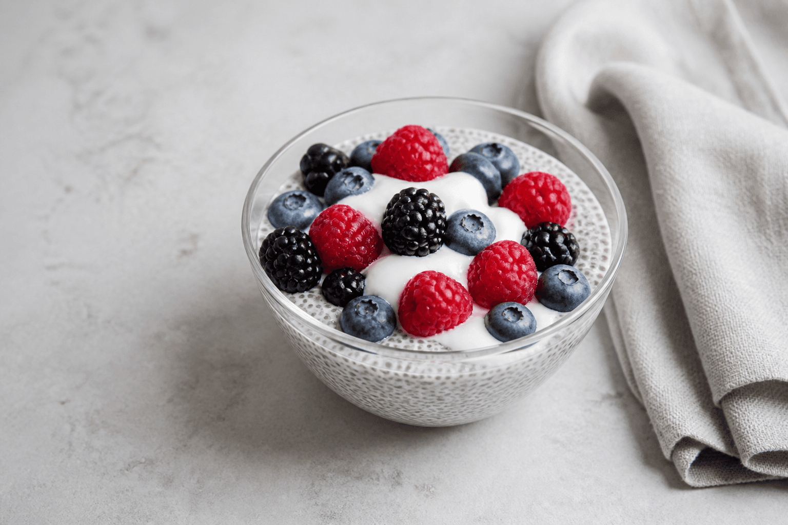 Chiagrød med bær serveret i glasskål med yoghurt og blandede bær.