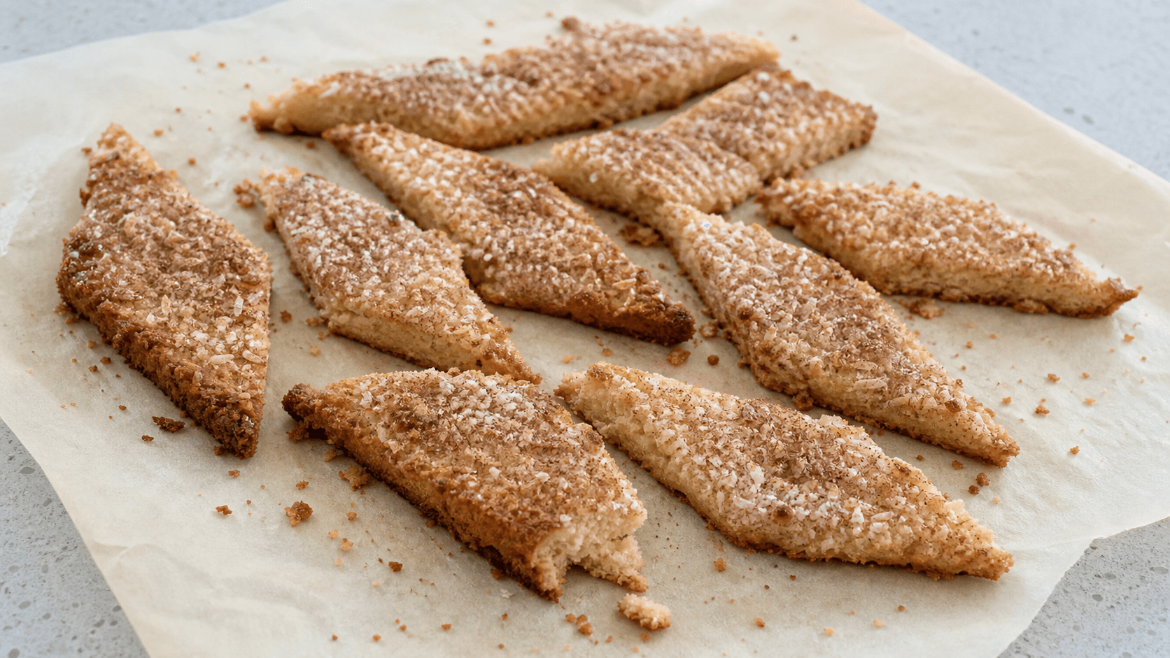 Hjemmebagte fedtebrød skåret i ujævne skrå stykker med kokos, kanelsukker og sprøde kanter.