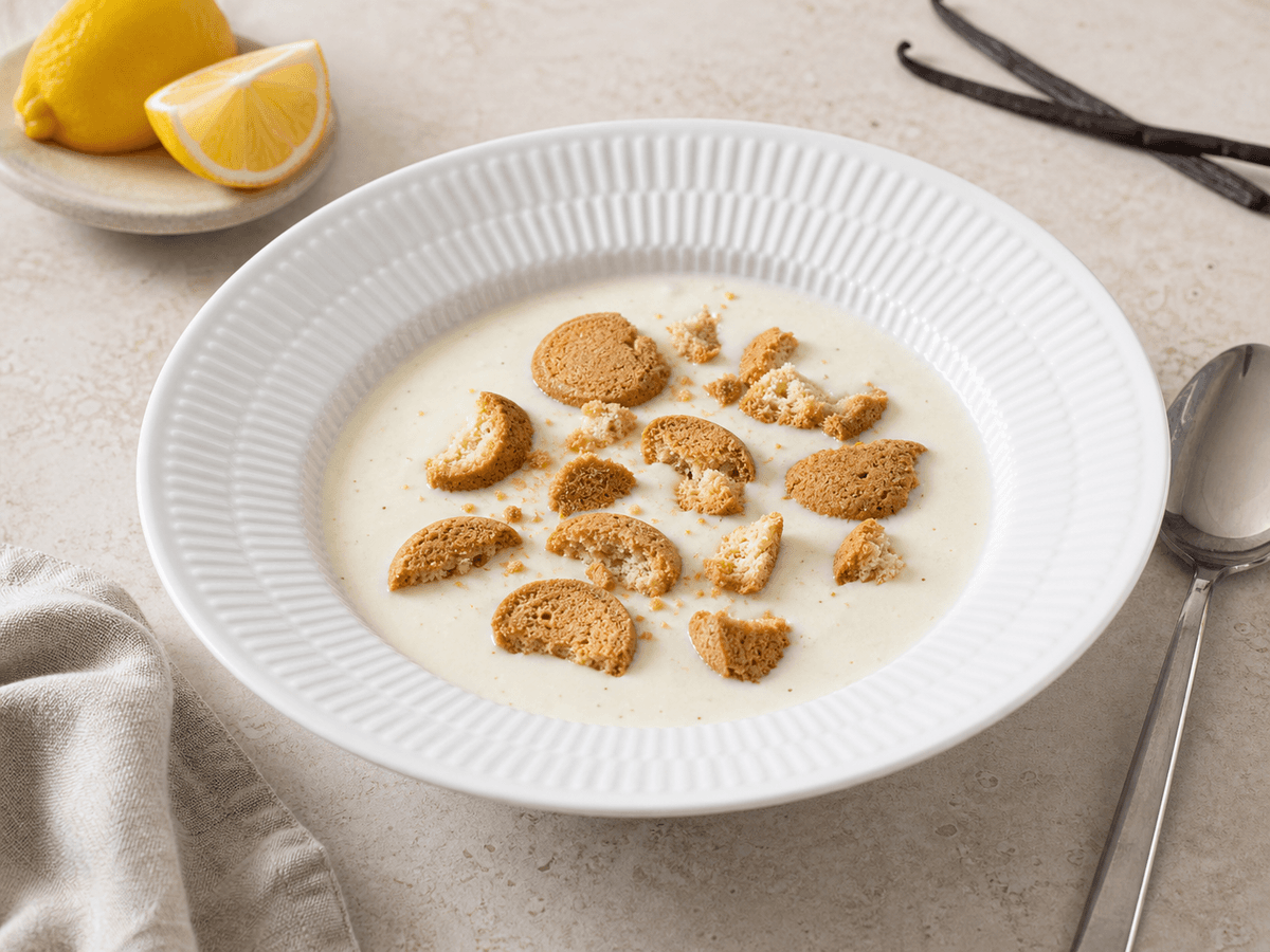 Koldskål uden kærnemælk i skål med kammerjunkere, citron og en mild yoghurtcue ved siden af.