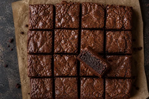 Brownie skåret i firkanter med krakeleret top og fudgy midte.