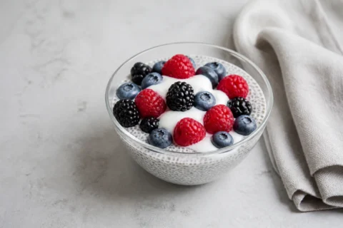Chiagrød med bær serveret i glasskål med yoghurt og blandede bær.